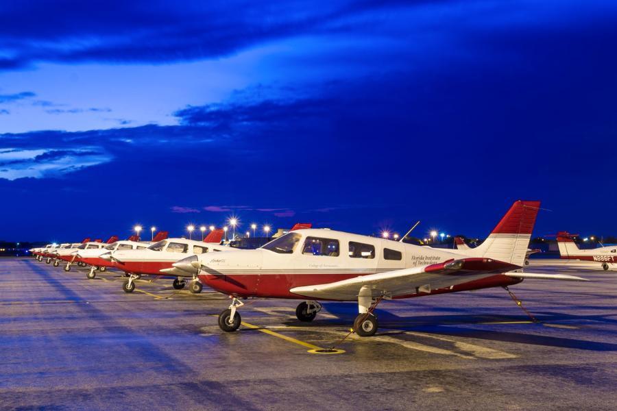 Florida Tech planes at night in formation on the tarmac.