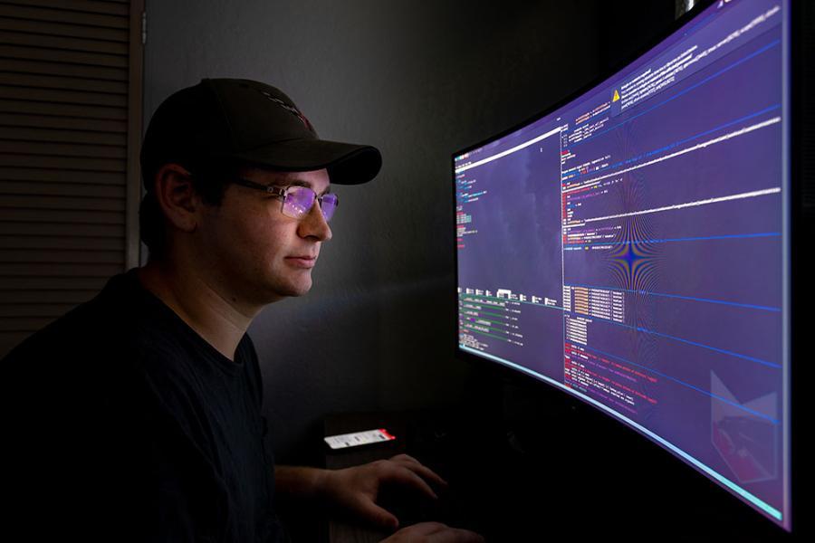 A Florida Tech computer science student reviews code on a large desktop monitor