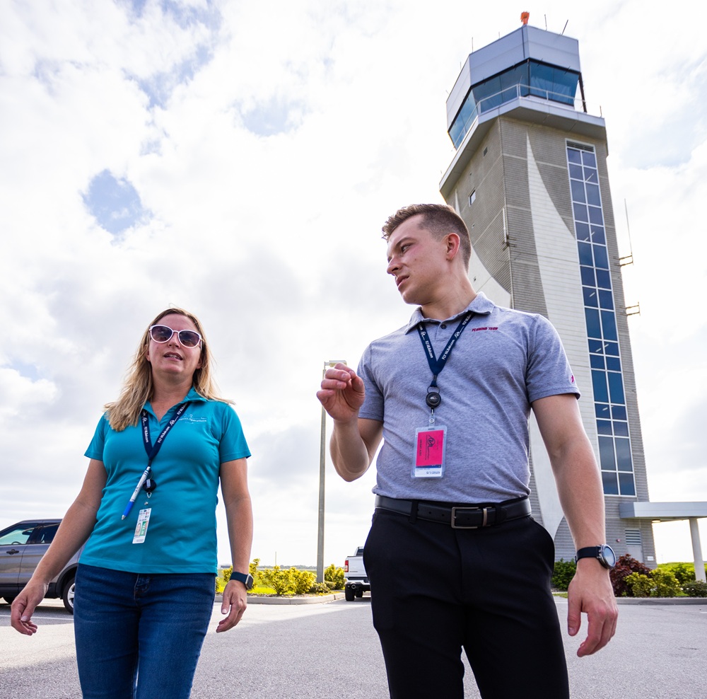 Two people walking near the control tower at Melbourne Orlando International Airport.