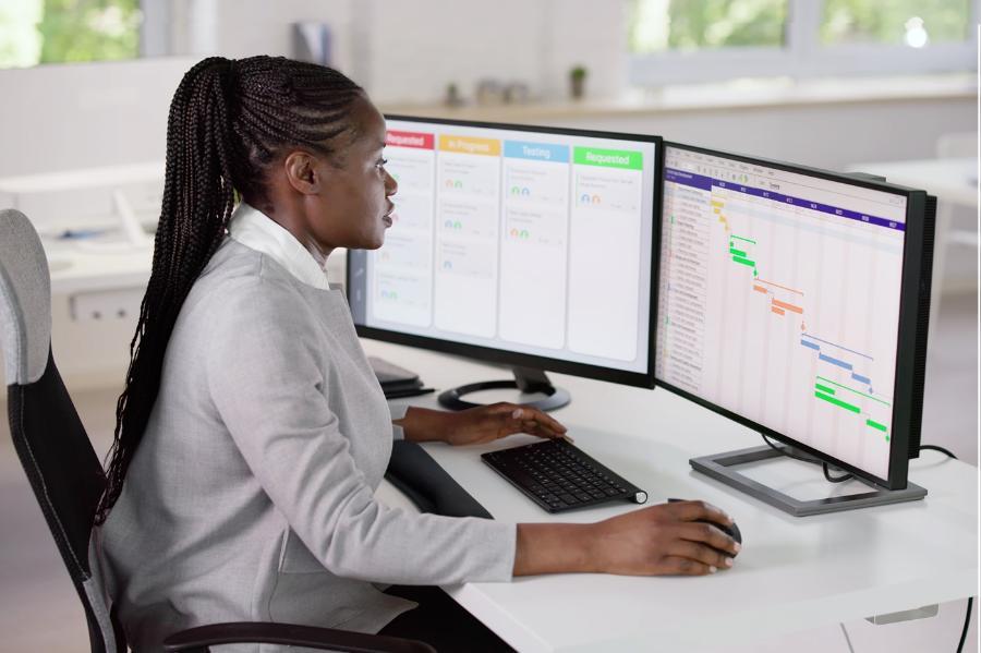 A project manager sitting at a desk, working with project management software