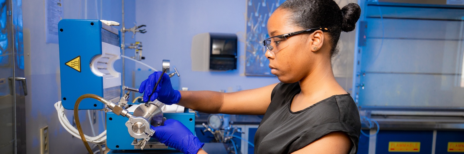 A chemical engineering graduate student working with a split tube furnace