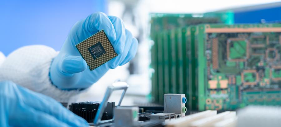 A gloved hand holding a cpu in a cleanroom.