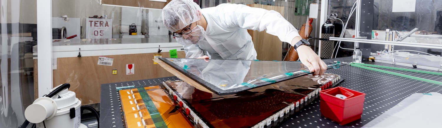 In the high bay clean room a student assembles a detector panel destined for the LHC at CERN.