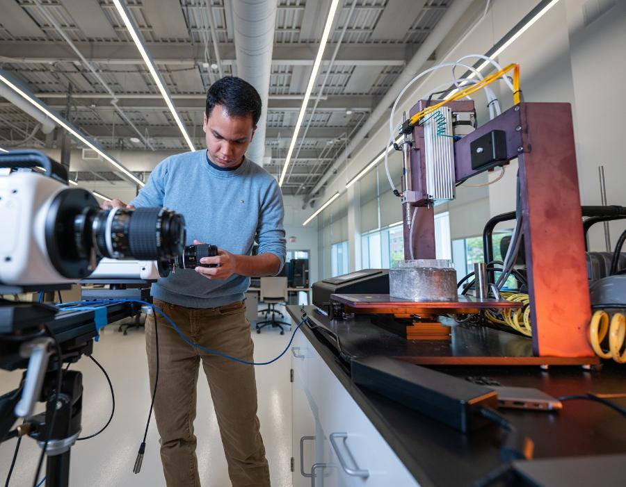 Student setting up for materials testing with high speed camera and testing rig.