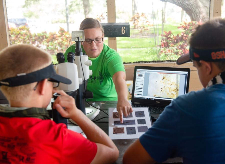 A student teaching two young people about environmental issues affecting the Indian River Lagoon.