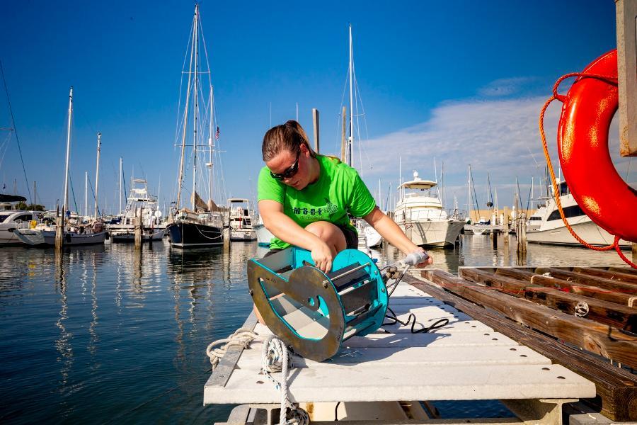 A student works with a conductivity, temperature, depth device that helps to assess specific conditions in the ocean.