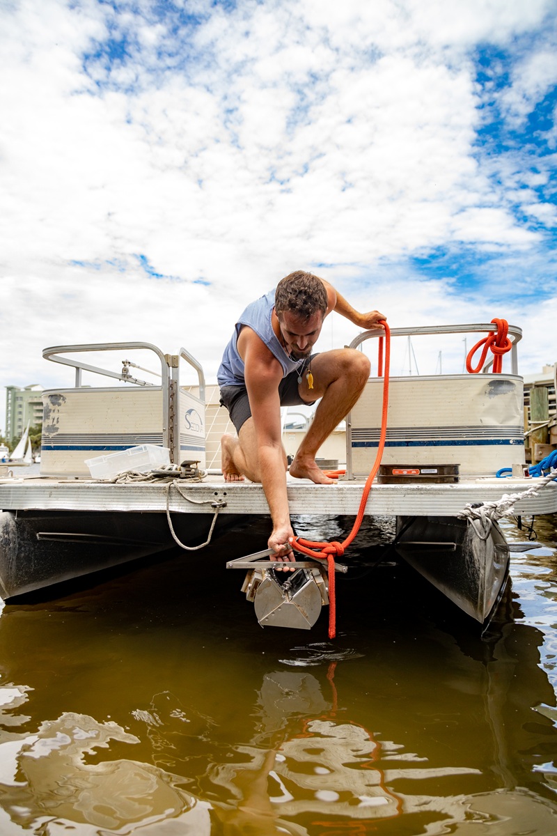 A student collects lagoon sediment samples for analysis