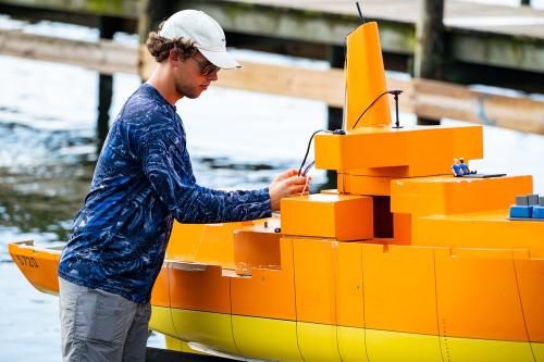 A student prepares to launch Florida Tech's 1/23rd-scale self-propelled model of the U.S. Navy’s R/V Melville, used for data collection and ship dynamics experimentation.