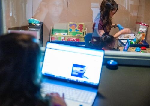 An ABA practitioner working with a child being observed from an observation room.