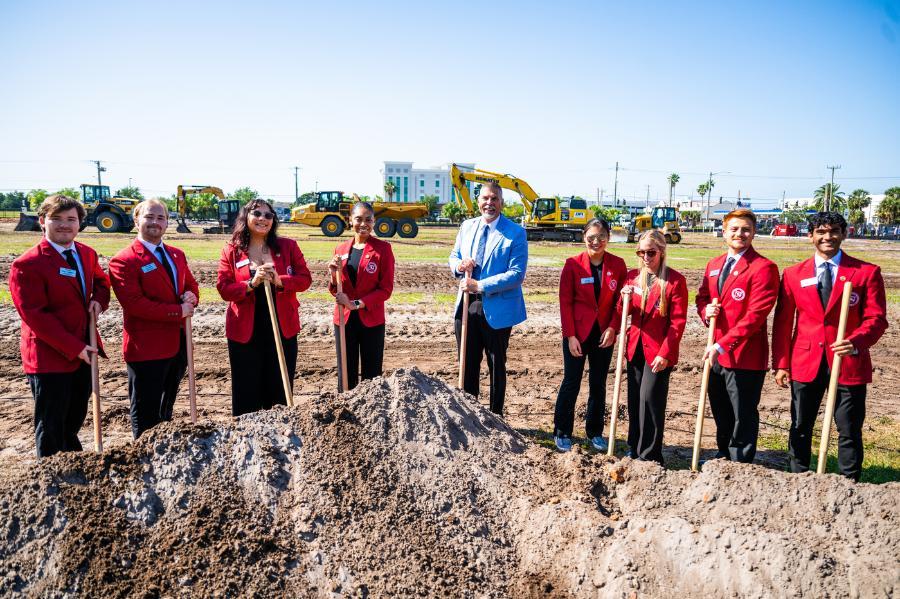 President Nicklow with several President's Ambassadors, posed behind a dirt mound with shovels.