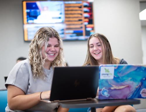 Two students working together in the College of Business lobby.