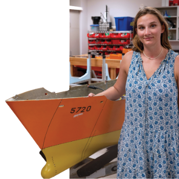 Student standing next to boat in workshop.