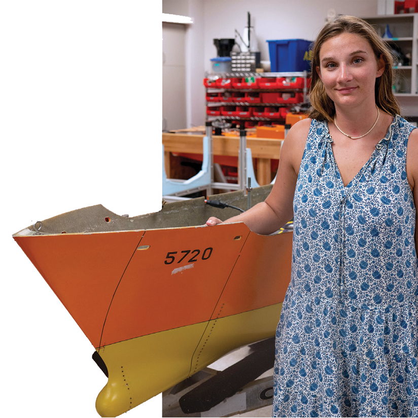 Student standing next to boat in workshop.