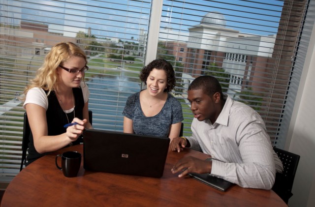 Three students looking at a laptop