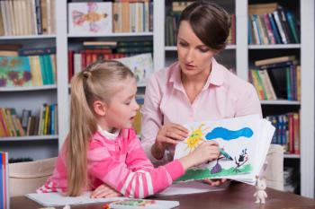 A young girl pointing a crayon at her drawing