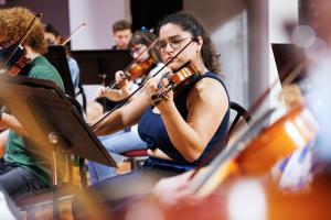 Student playing the violin in the string orchestra