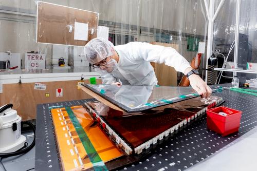 A student works in a cleanroom assembling a particle detector for CERN.