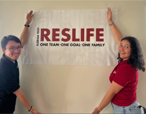 Resident Assistants smiling by Reslife Sign