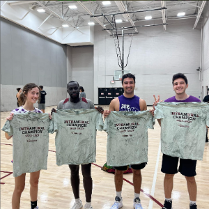 Students from the champion intramural basketball team smiling and holding shirts that read
