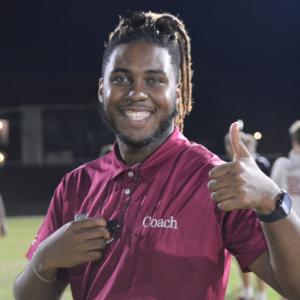 A student official smiling and giving a thumbs up at an intramural sports competition.