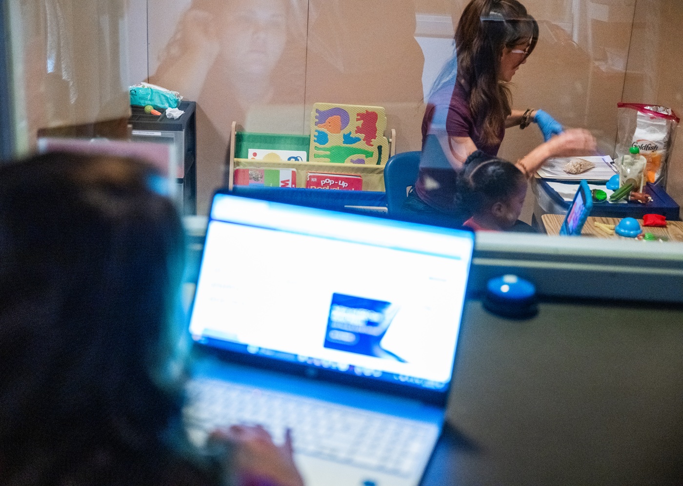 A researcher observing a technician a the Scott Center for Autism Research working with a child.
